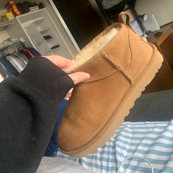 a reviewer holing the short Ugg boot in brown 