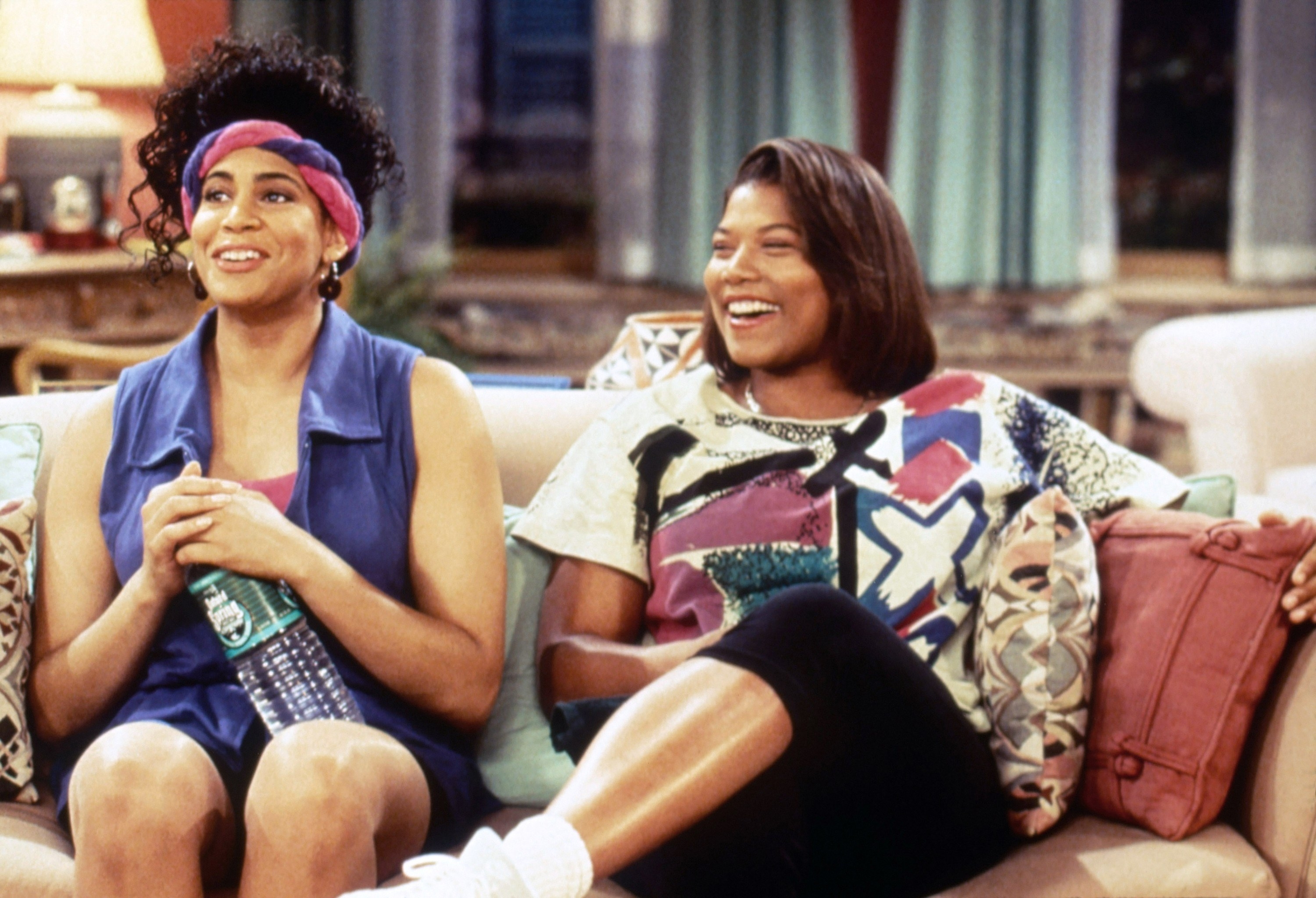 Kim Coles and Queen Latifah laughing on the couch.