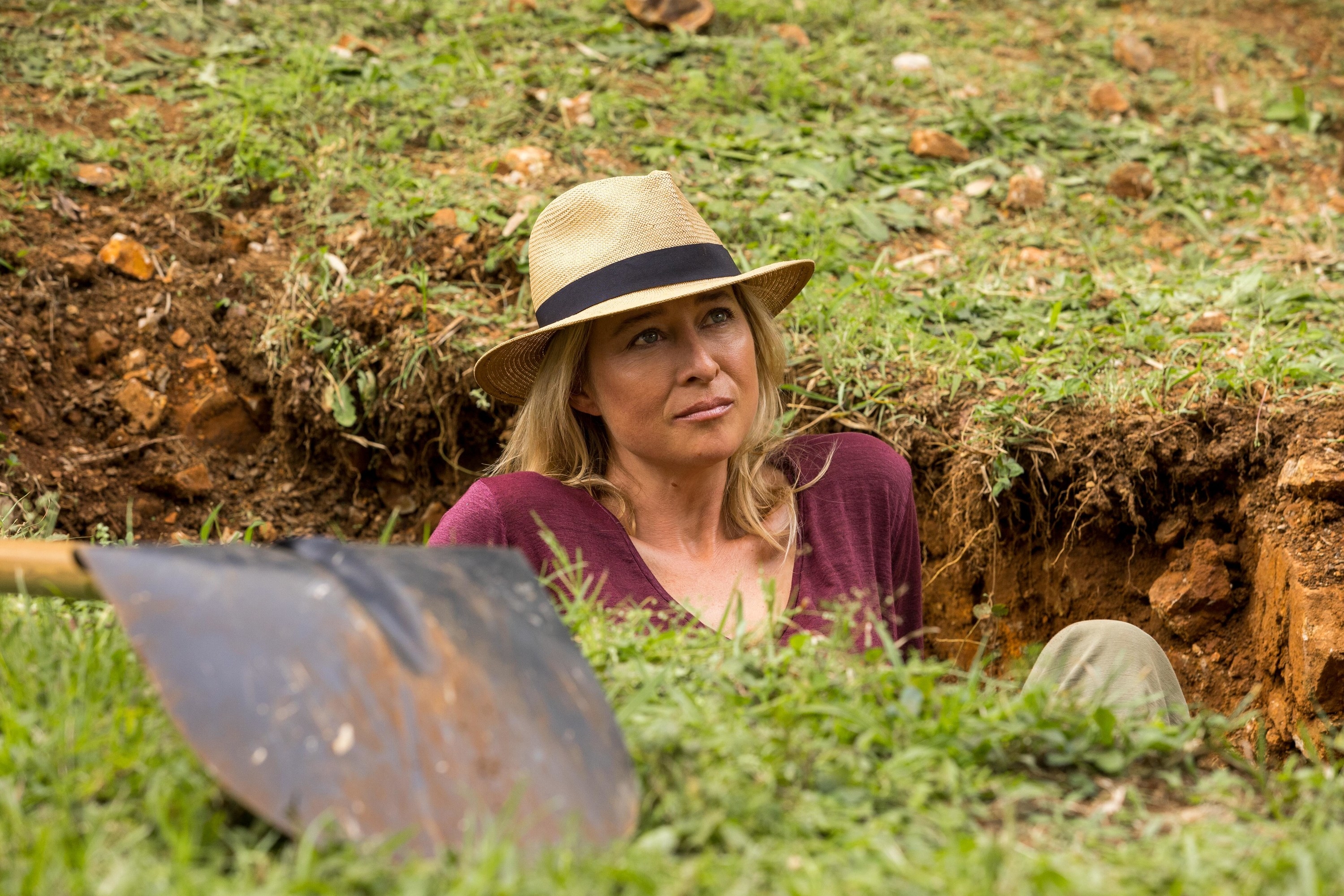 A woman sitting in a grave she dug