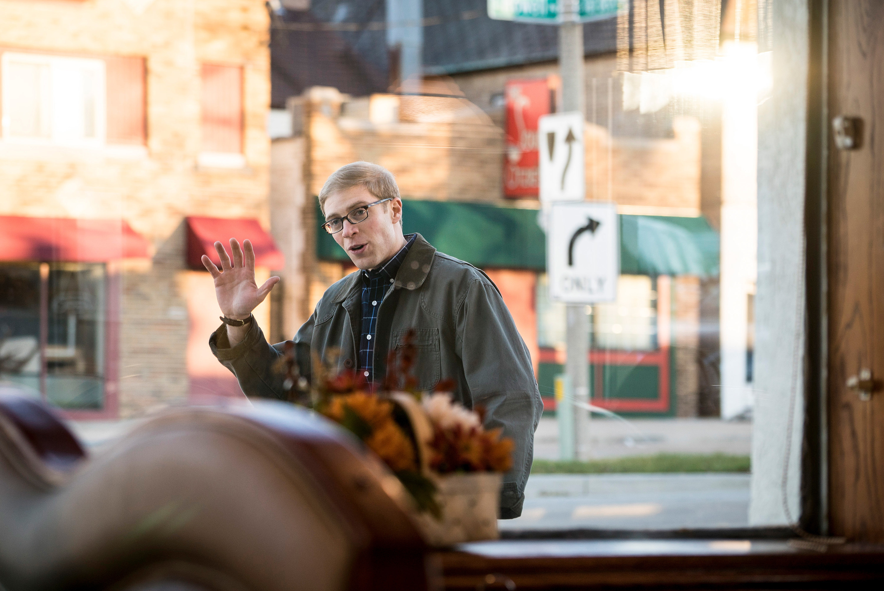 Joe Pera waving as he walks by a window.