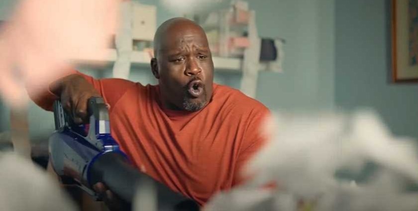 Shaq uses a leaf blower in a work room