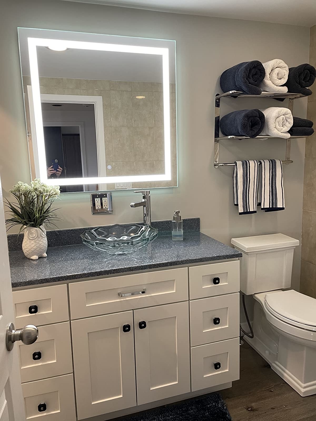 Reviewer photo of the mirror installed in their bathroom and lit up, showcasing the LED lights surrounding the frame