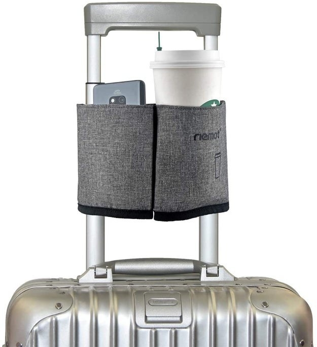 gray cup caddy holding a Starbucks coffee and cellphone attached to a carry-on suitcase handle
