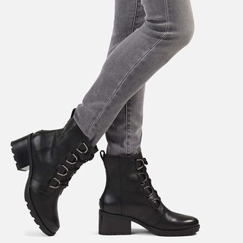 a model wearing a pair of gray jeans with the heeled lace-up booties in black 