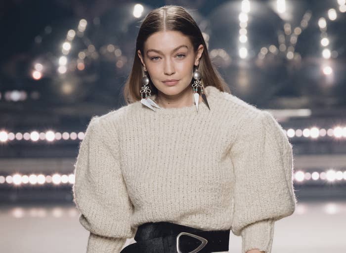 Gigi wears a sweater while walking a runway