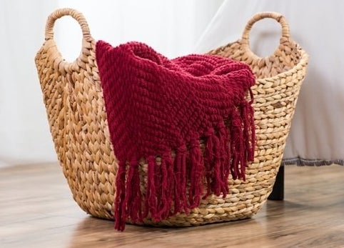 a wicker basket with handles hold a blanket