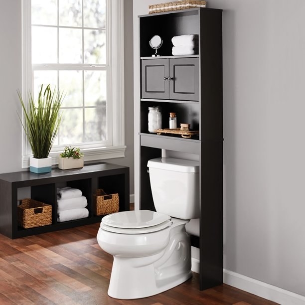a bathroom organizer over the toilet with two shelves and a drawer