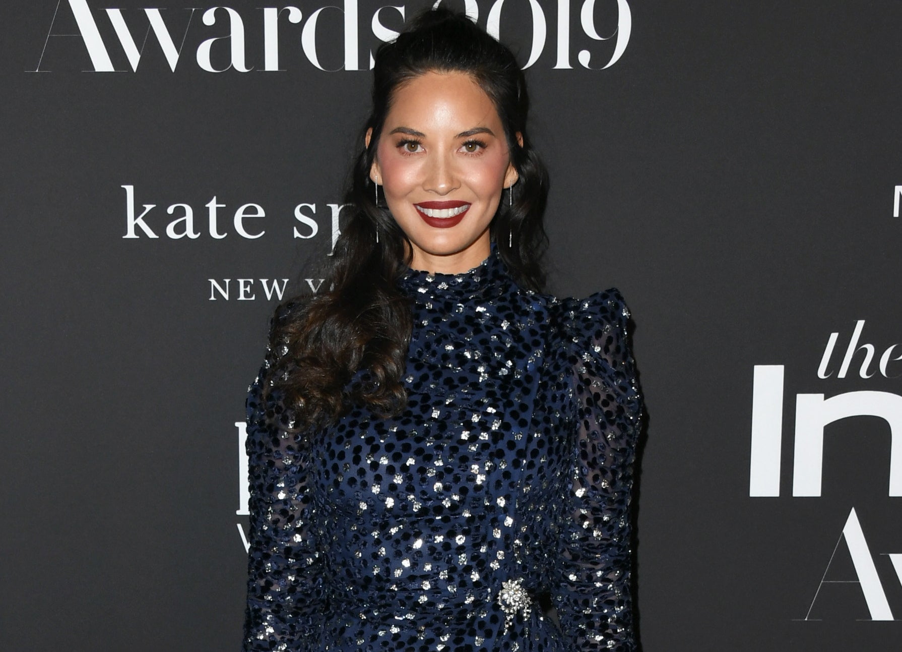 Olivia smiles widely on a red carpet