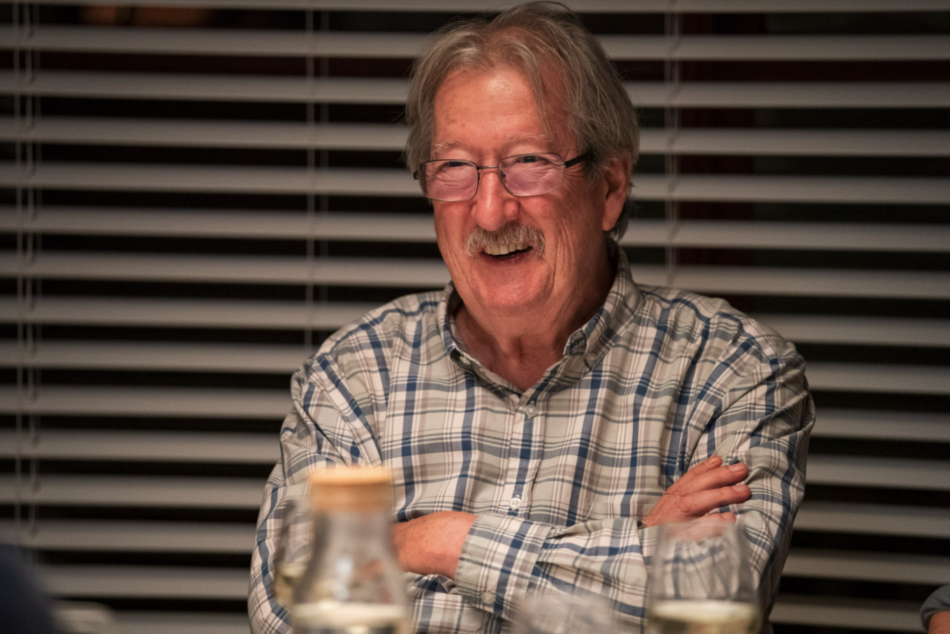 Michael Caton laughing while sitting down at a table