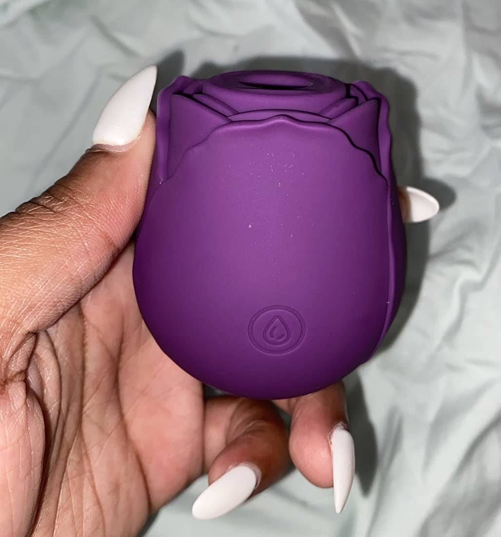 Reviewer holding purple rose-shaped vibrator