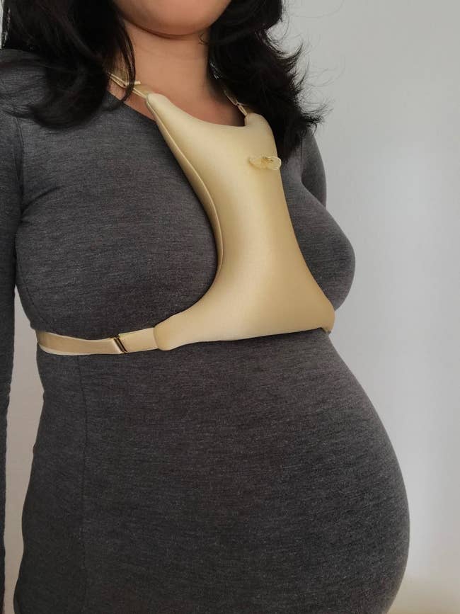 pregnant reviewer wearing the gold pillow across their chest between their boobs