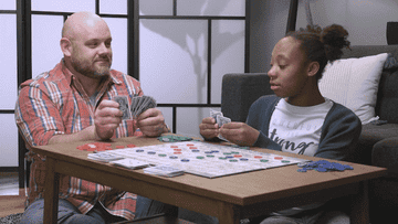 2 people playing the board game sequence on a coffee table