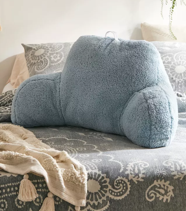 A large pillow with arms sitting on a bed