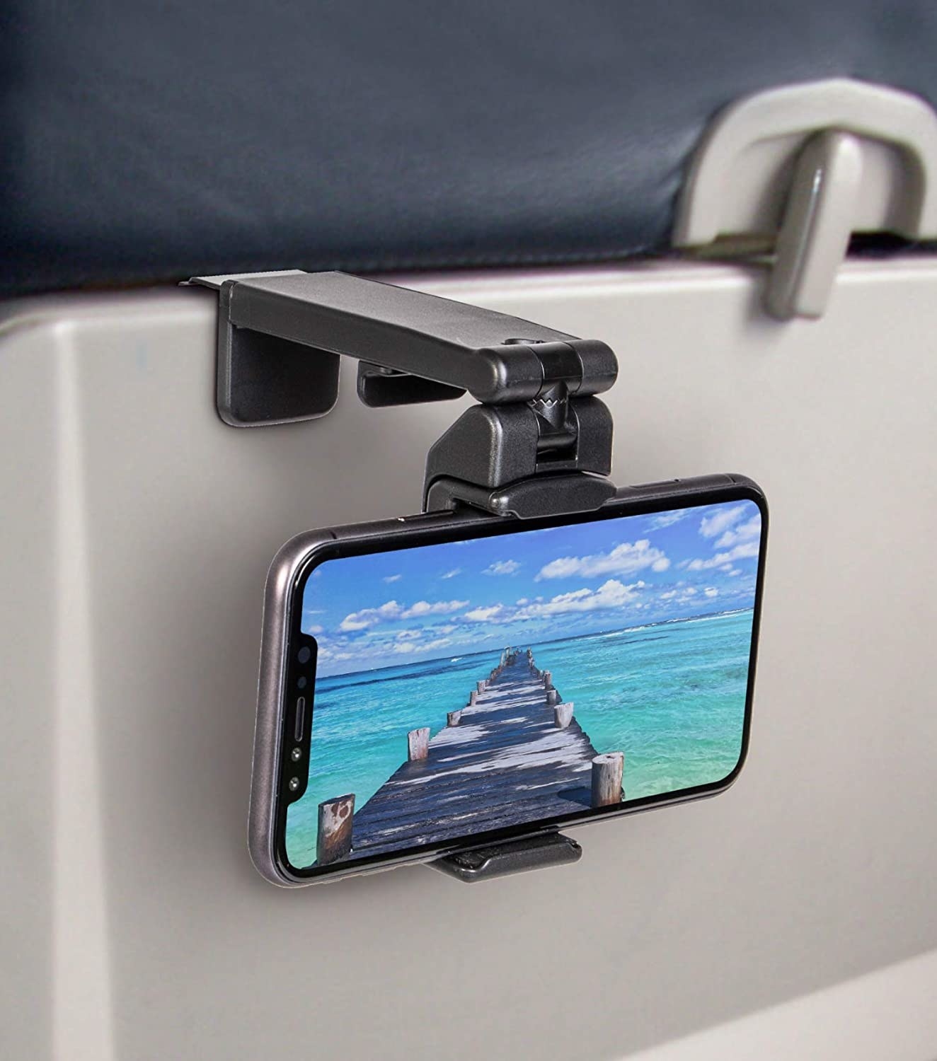 black phone mount clipped to smartphone with beach screen on back of plane seat