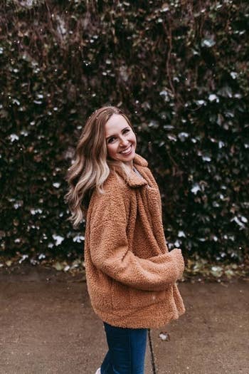 Reviewer wearing camel colored fleece jacket, stops astatine the thigh