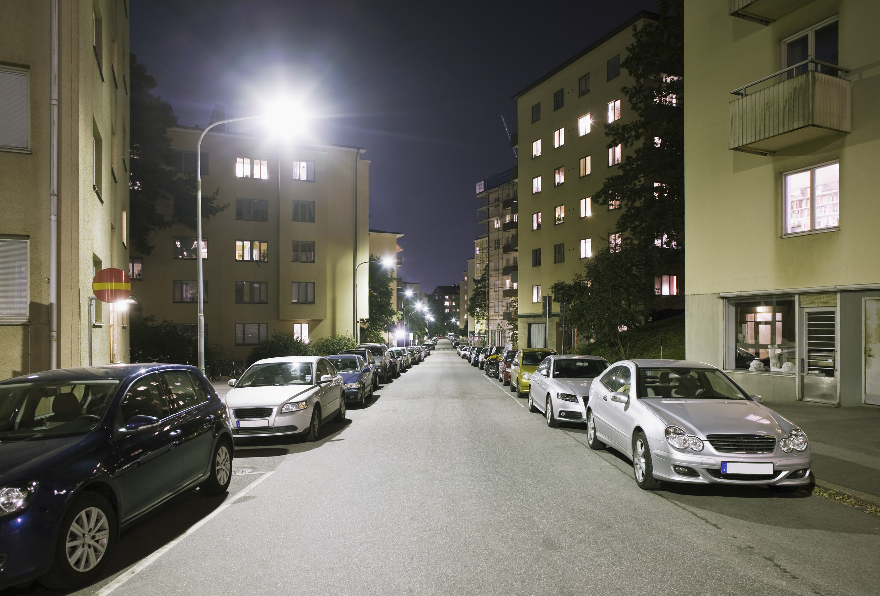 A street with cars parked along the side at night