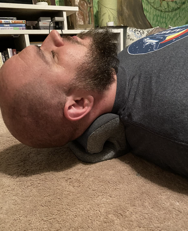 reviewer laying on the neck pillow 