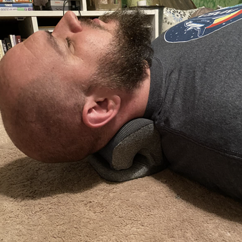 reviewer laying on the neck pillow 