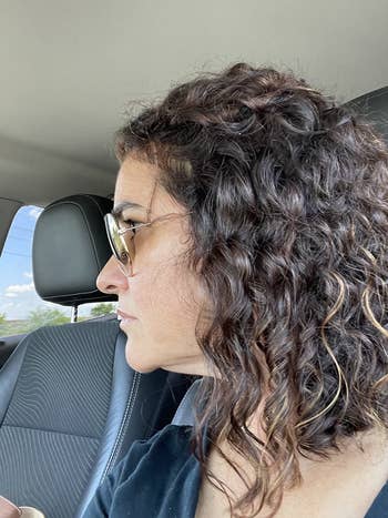 reviewer wearing the spray showing it kept their curls defined and shiny while reducing frizz