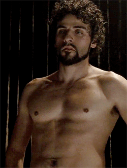 GIF of Oscar Isaac with curly hair, shirtless, licking his lips