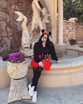 reviewer wearing bright red flare skirt, black tights, and black cardigan with Minnie Mouse ears
