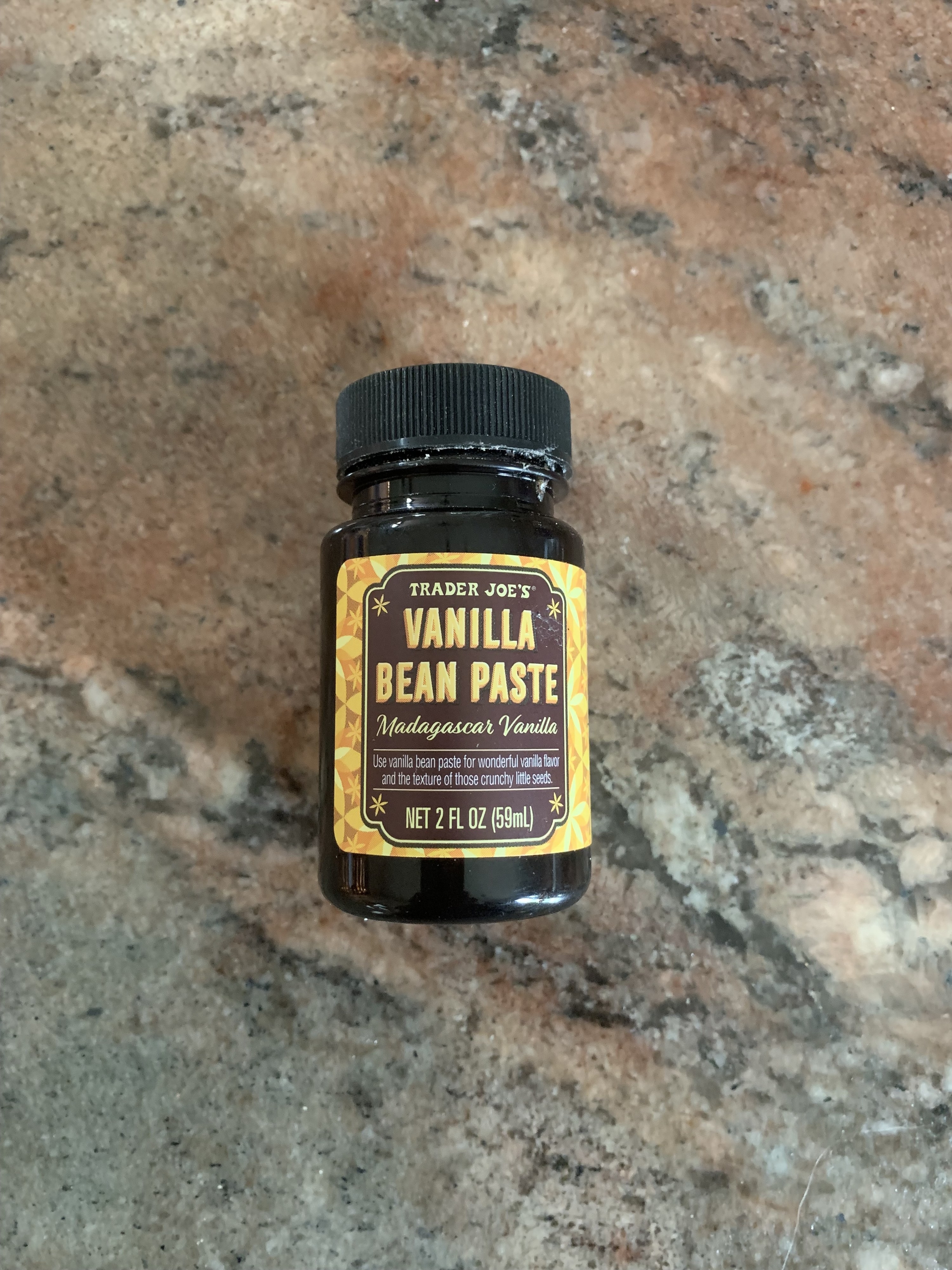 The small bottle of vanilla bean paste laying on the counter