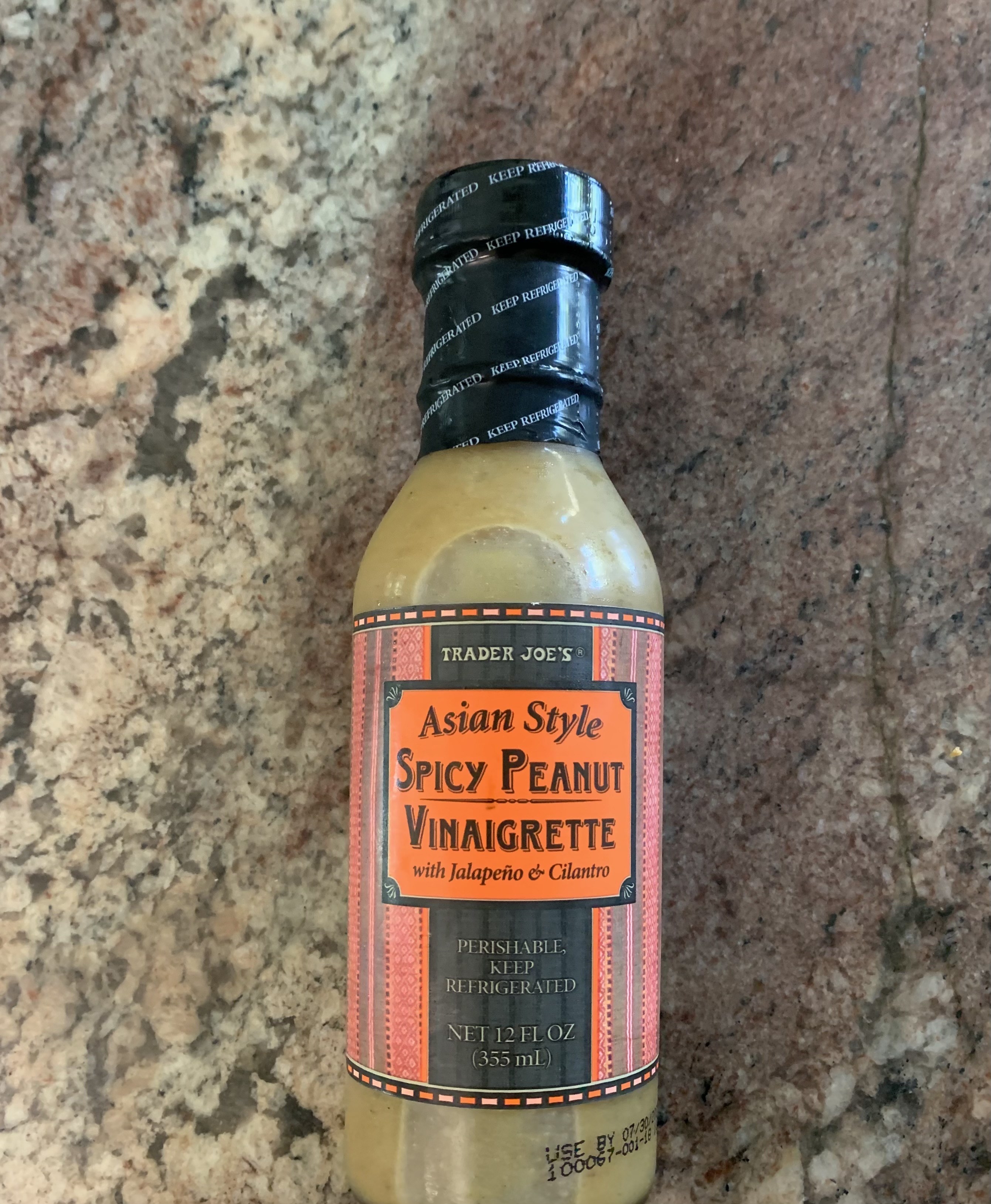 The Asian Style Spicy Peanut Vinaigrette bottle is on the counter