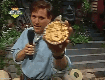 Host of the show &quot;Legends of the Hidden Temple&quot; holds a gold medallion up to the screen