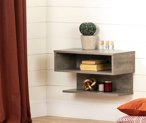 the floating shelf in weathered oak mounted on a white wall