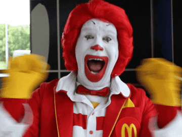 Ronald McDonald scrunches his fists in joy and holds them up to his face