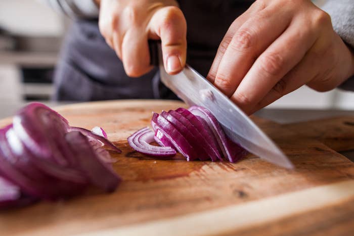 A close up of someone slicing onions