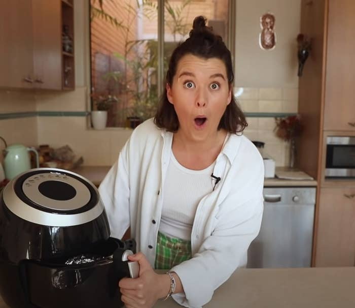 Zeta looking shocked in her kitchen, opening her air fryer.