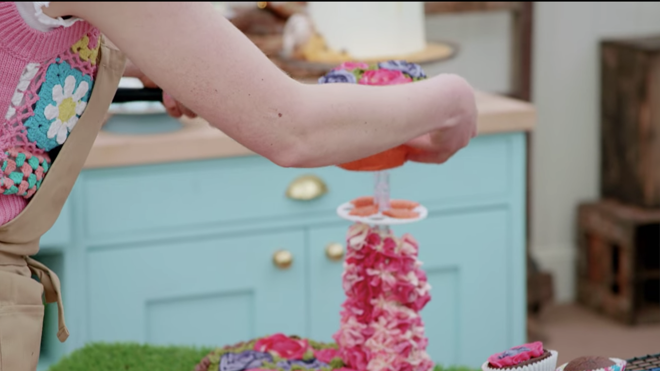 Someone setting a cake on a stand