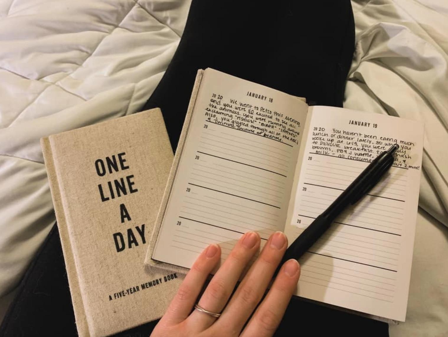 reviewer photo of the front of the journal that says &quot;one line a day&quot; and an open journal with a pen on it and the first two lines filled out