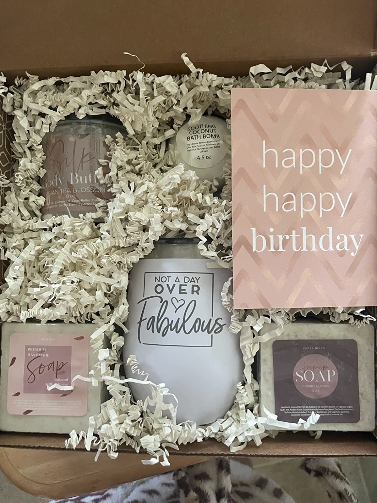 the basket with the two soaps, body butter, bath bomb, wine tumbler and a happy birthday card
