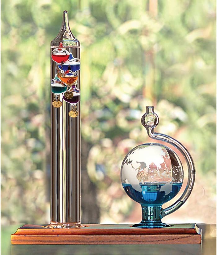 the cylinder thermometer with the floating bulbs at the top next to the glob barometer with blue liquid floating near the bottom