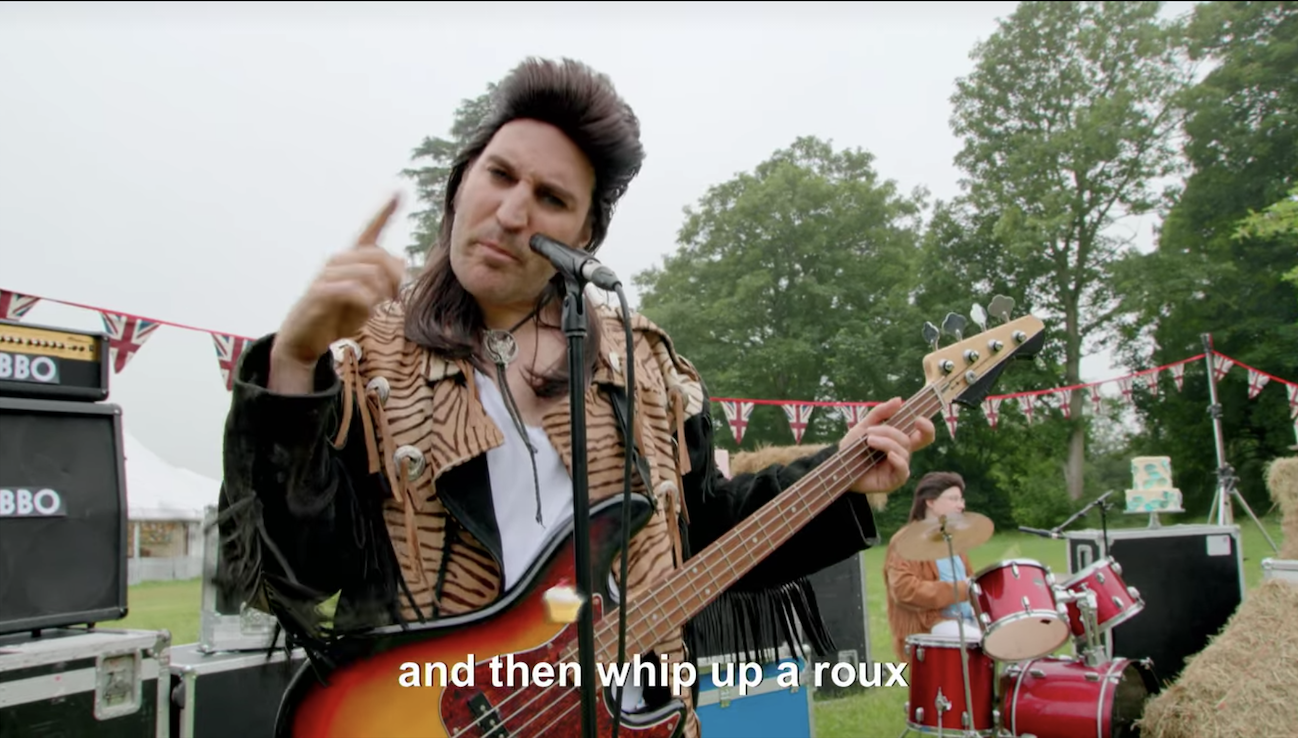 Noel in a mullet wig singing &quot;and then whip up a roux&quot;