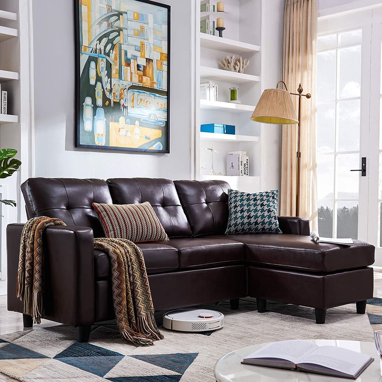 A brown faux leather couch with colorful blankets and pillows
