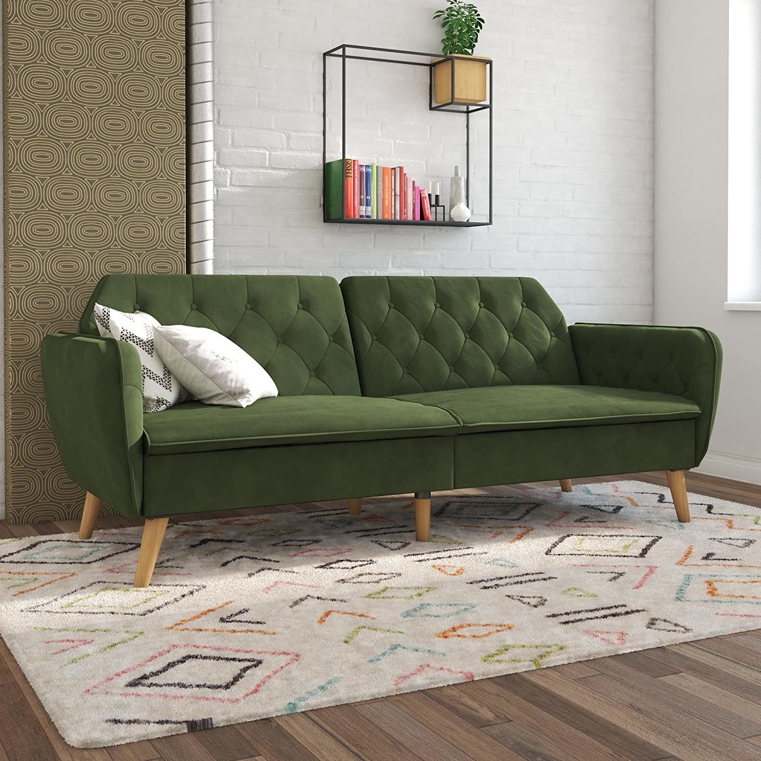 A green couch in a white room with colorful rug