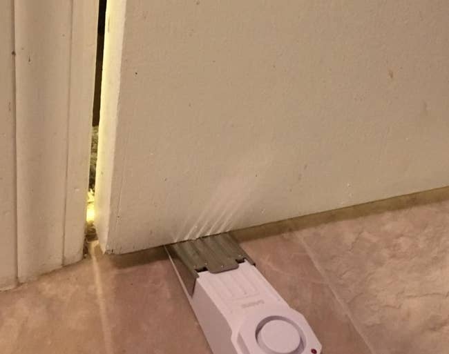 a reviewer photo of the wedge alarm inserted underneath a door