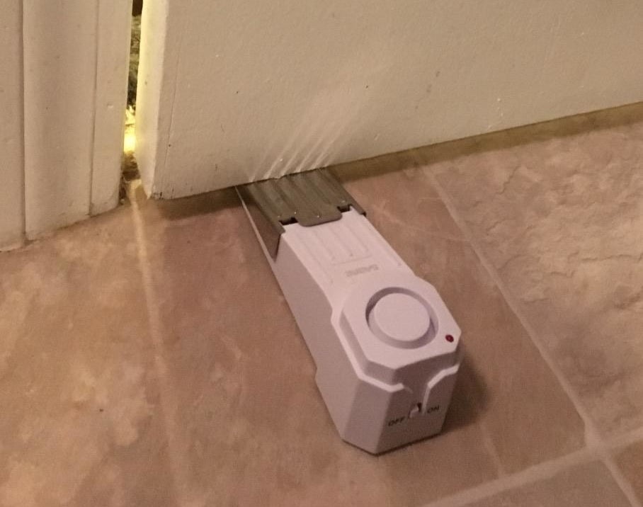 a reviewer photo of the wedge alarm inserted underneath a door