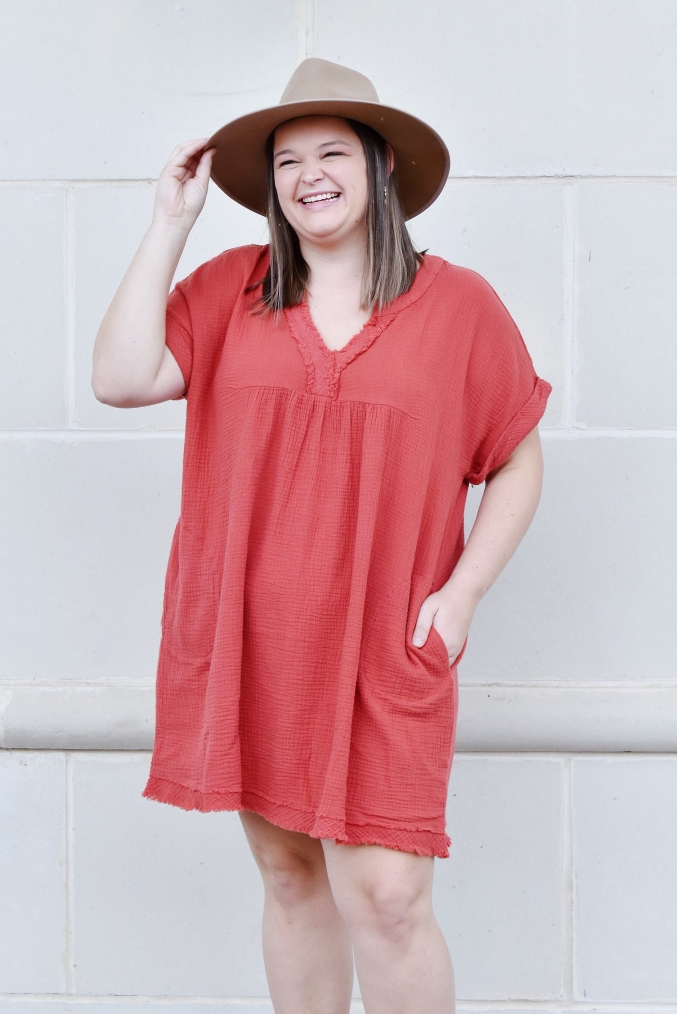 model in short sleeve v-neck rust orange tunic with hands in pockets