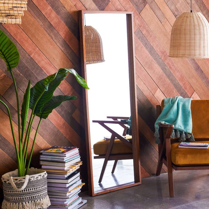 the wooden mirror next to a chair, plant, and books
