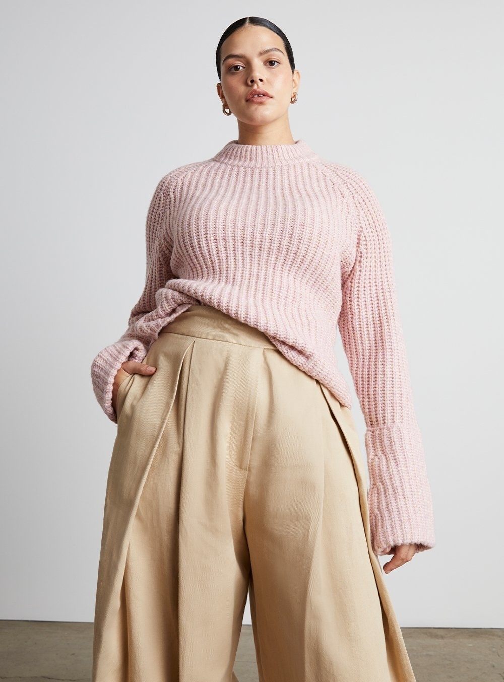 a model in a light pink sweater with oversized sleeves