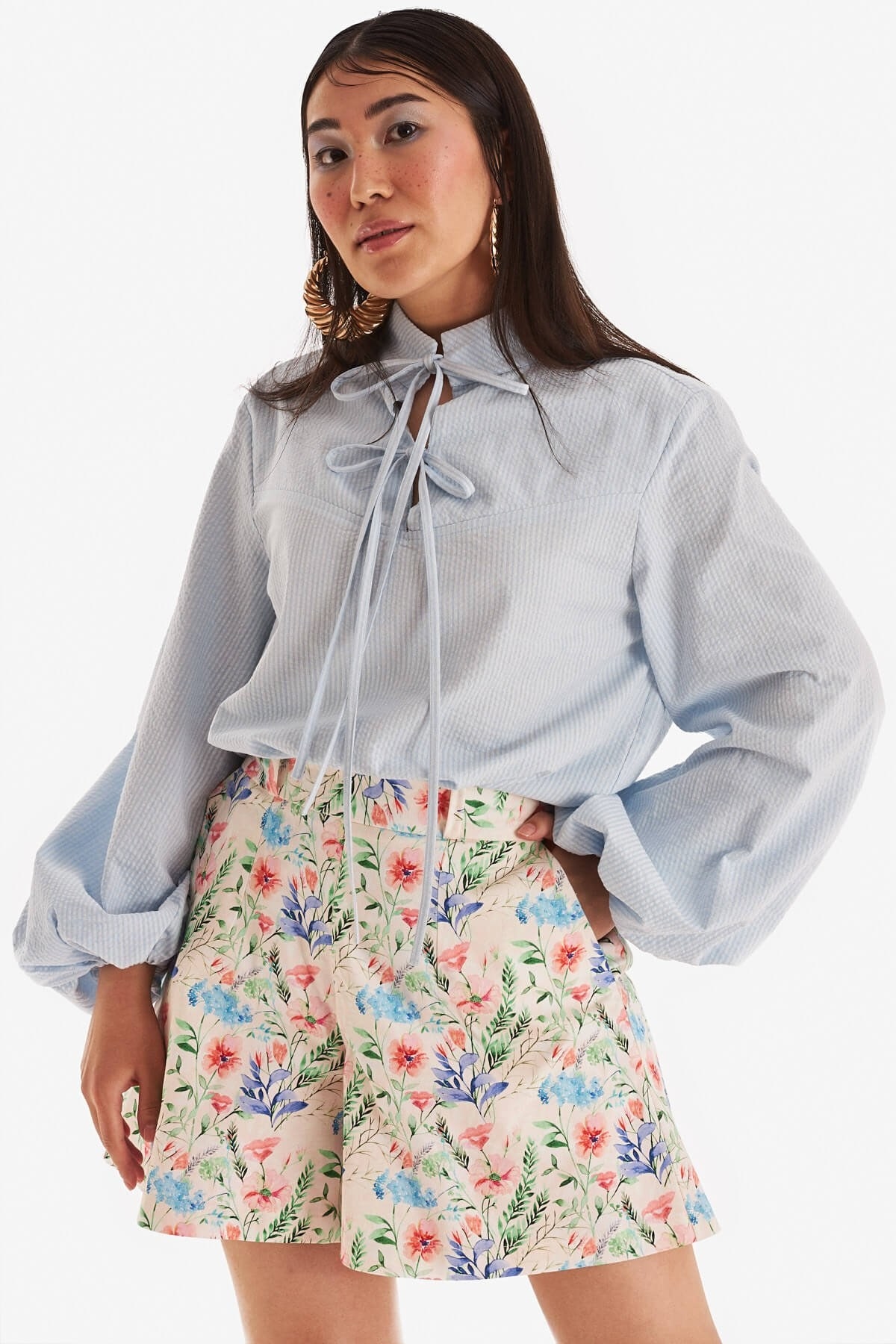 model in ballon-sleeve blue top and high-rise floral print shorts