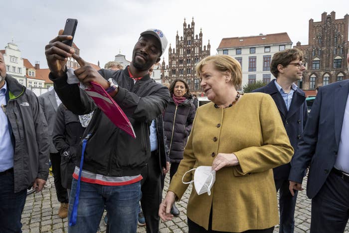 Angela Merkel poses for a photo with a man at a market