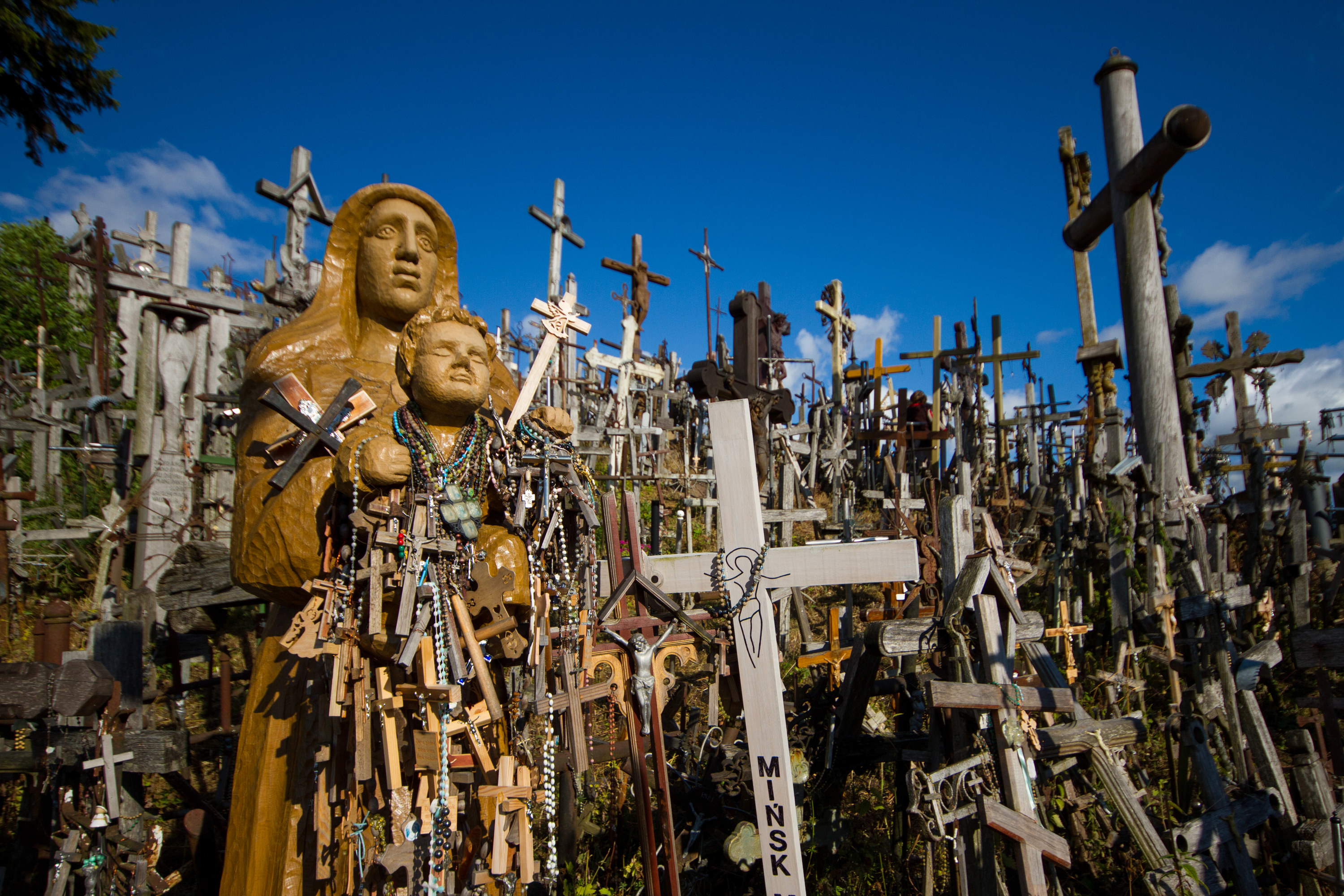 Hill covered in crosses of all sizes and a statue of a mother and child