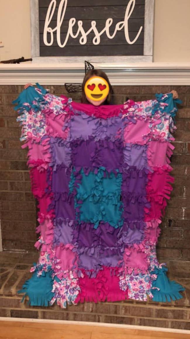 Reviewer's photo of their child holding up the quilt they made