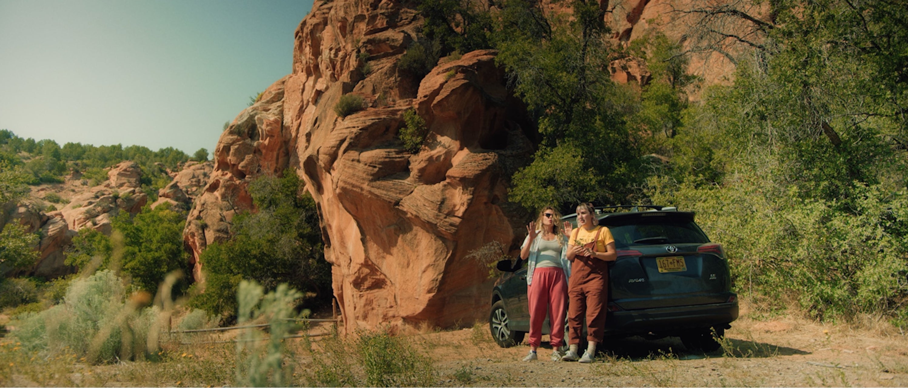 The sisters standing by a parked car near red rock mountains