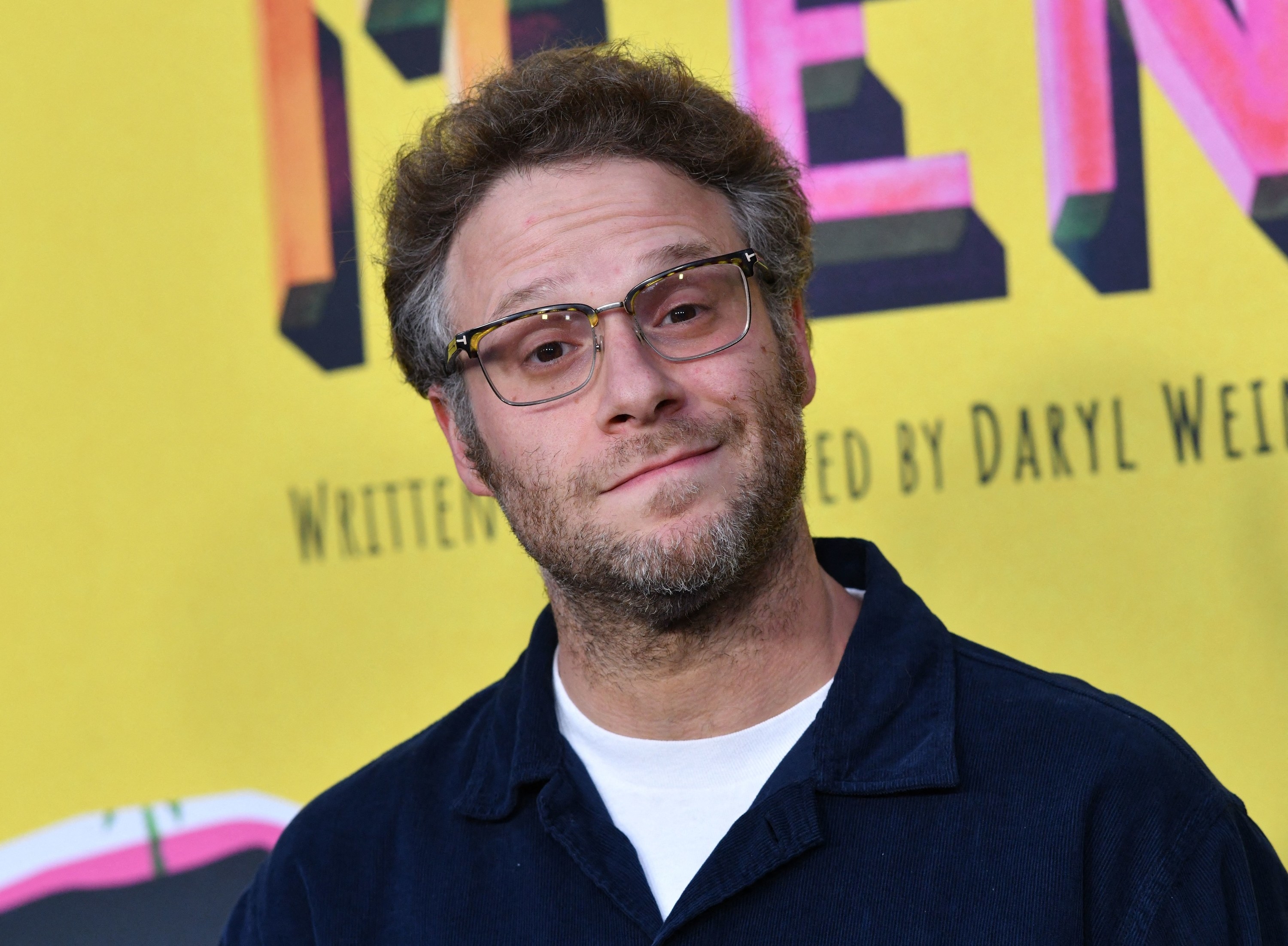 Rogen cocks his head to the side while smiling for a photo